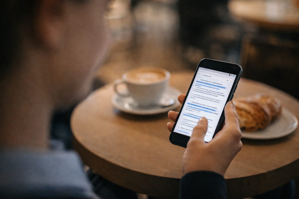 Patient in a cafe discovering a medical practice through a smartphone search