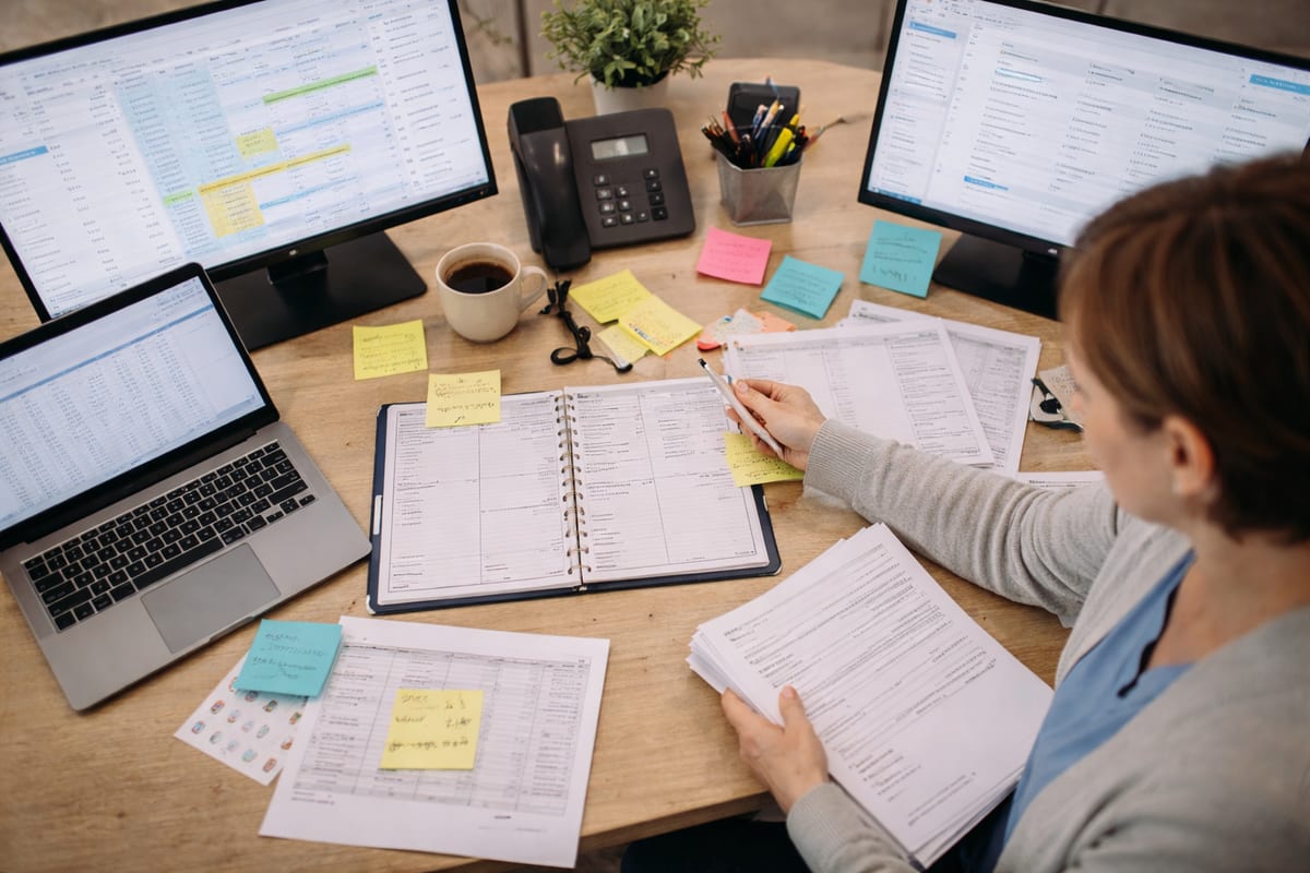 Cluttered clinic desk with multiple disconnected screens and scattered patient forms
